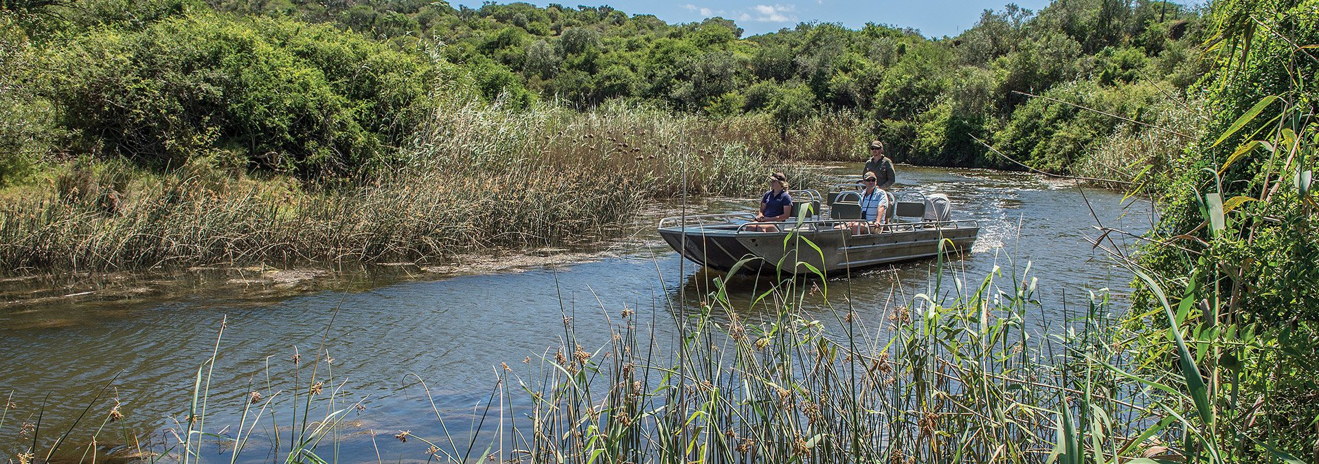 A river cruise boat on the Kariega River surrounded by green hills