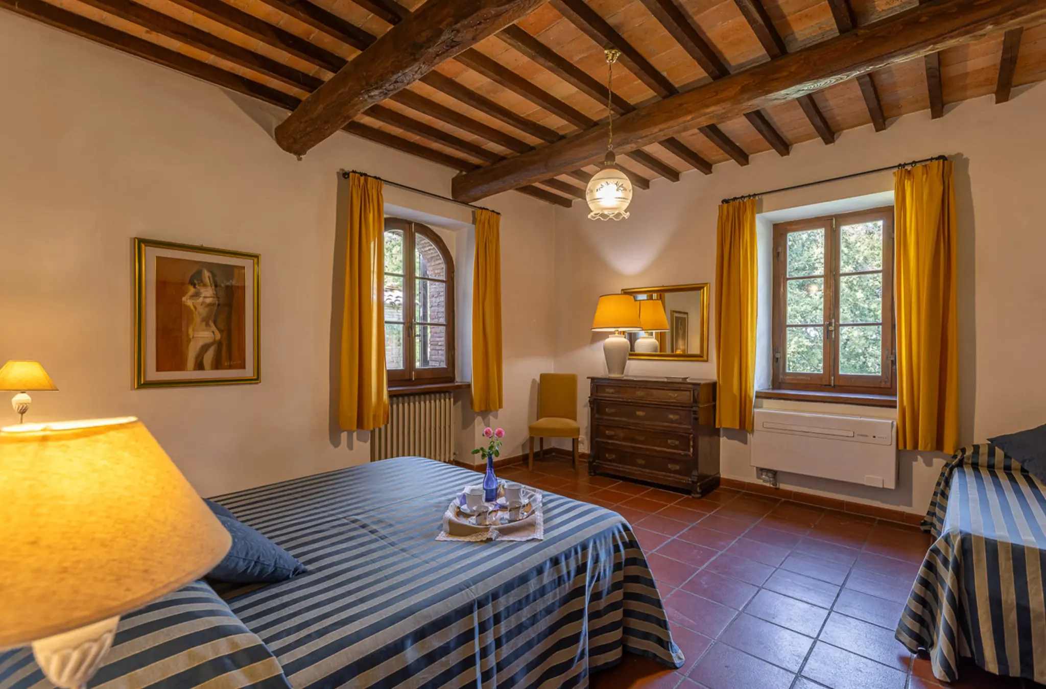 Bedroom with blue-stripe bedding and exposed wooden beams at Villa Serenzia